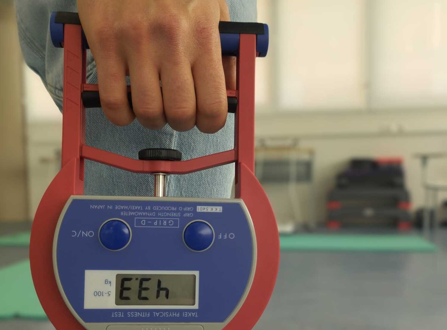 En hand håller i en apparat som mäter greppstyrka i handen.