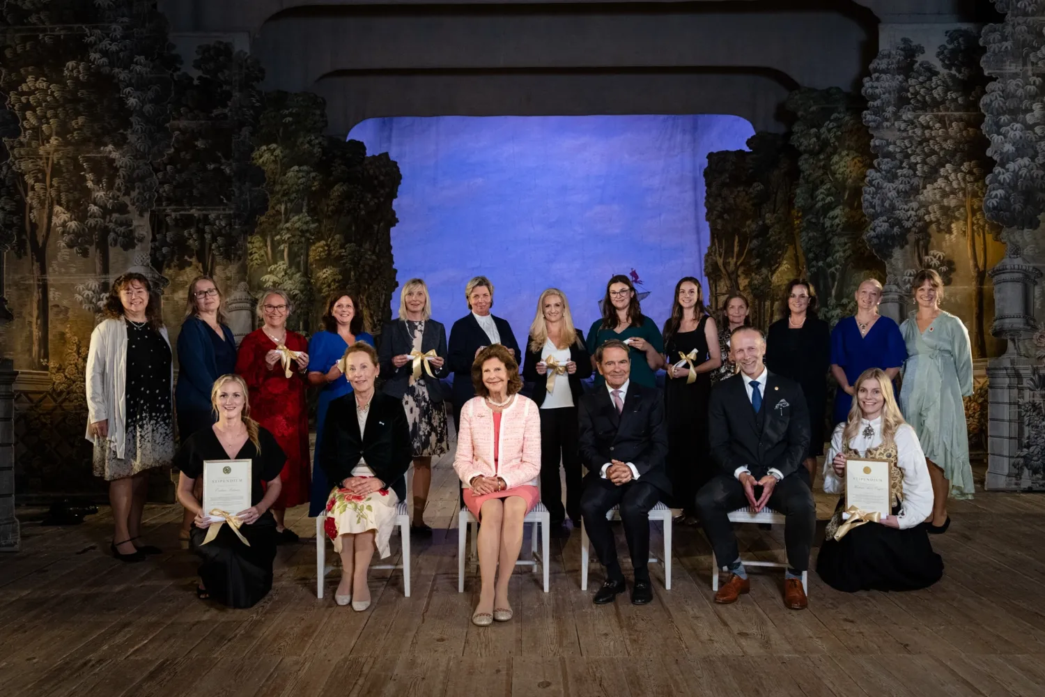 Drottningen tillsammans med Wilhelmina Hoffmann, Claes Dinkelspiel, och Martin Bergö, prorektor vid KI med diplomerade deltagare i magisterutbildning i demensvård för arbets- och fysioterapeuter
