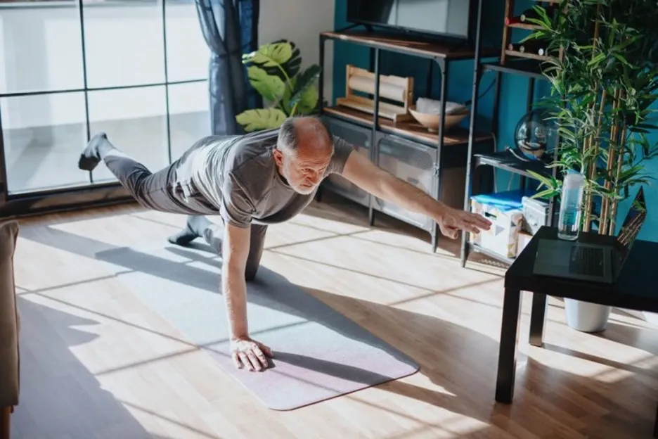 Bild på äldre man som utövar yoga.