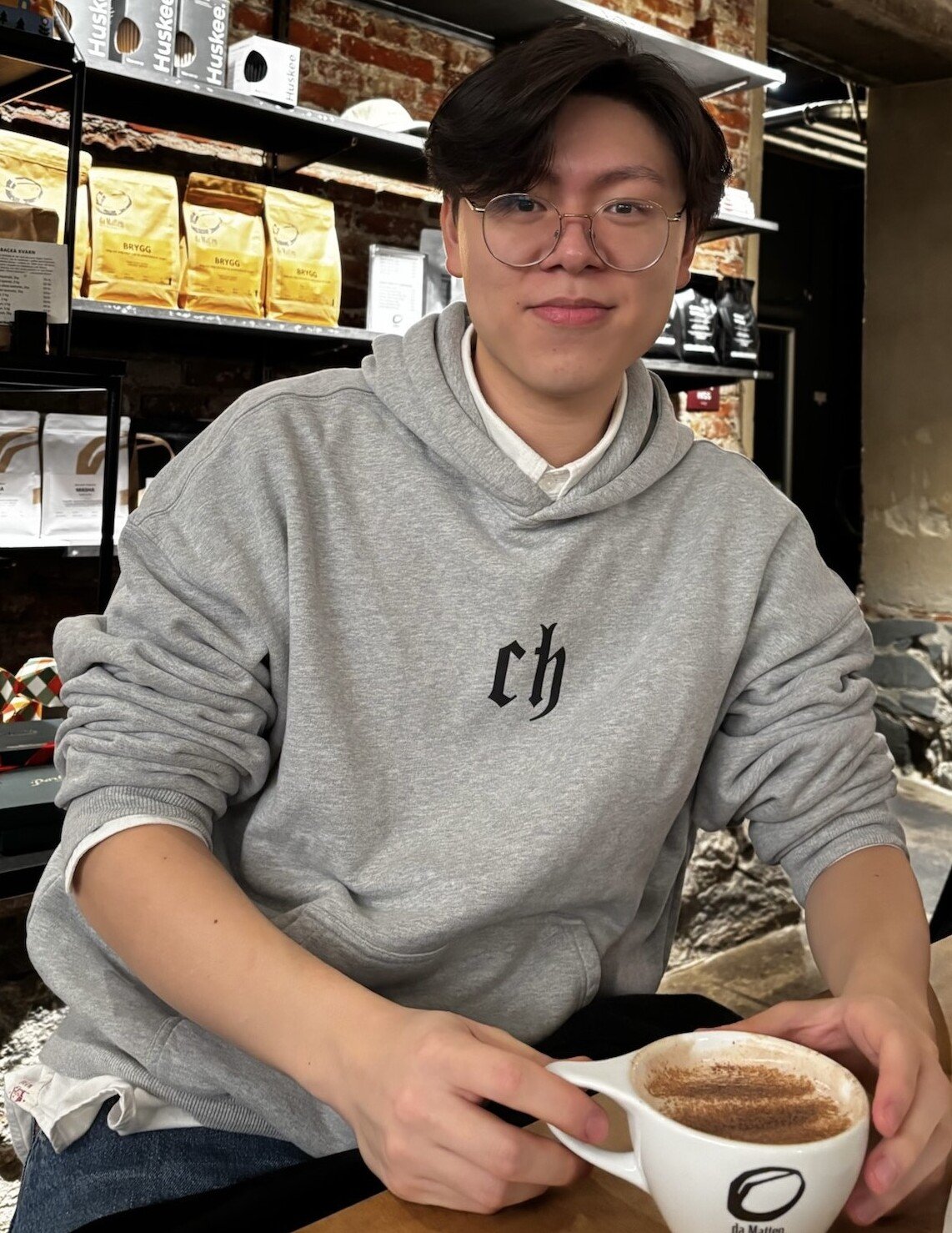 Alexander Suei med en kaffekopp i handen på ett café.