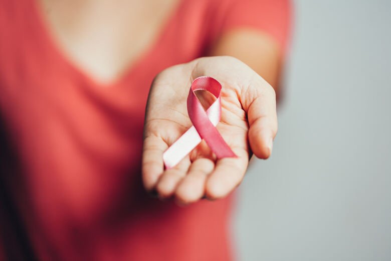 Woman holding pink breast cancer ribbon.