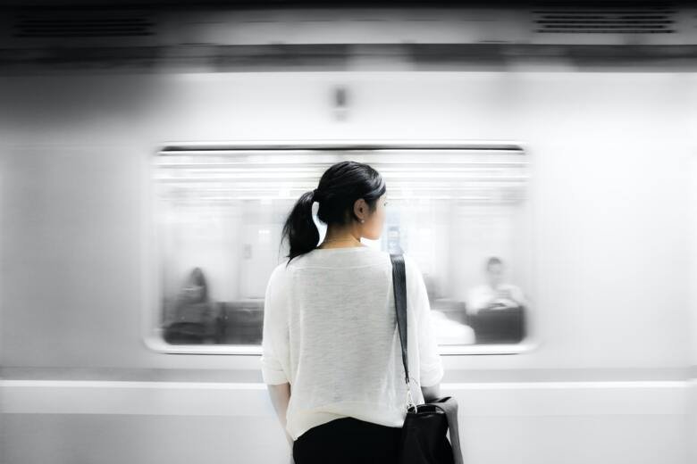 Kvinna som står i tunnelbanan, väntar på tunnelbanetåg.