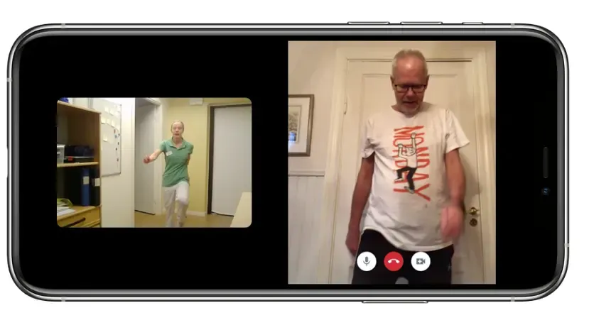 I en mobil ser man en äldre man som tränar efter en fysioterapeuts instruktioner