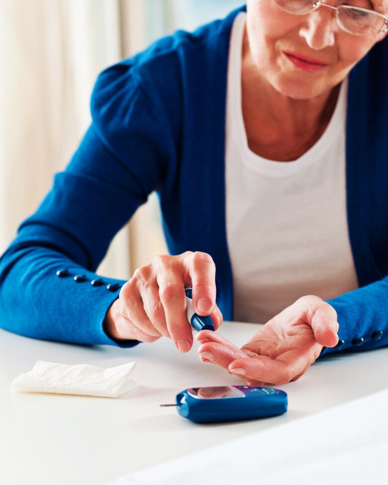 Blood glucose monitoring; woman stings her finger.