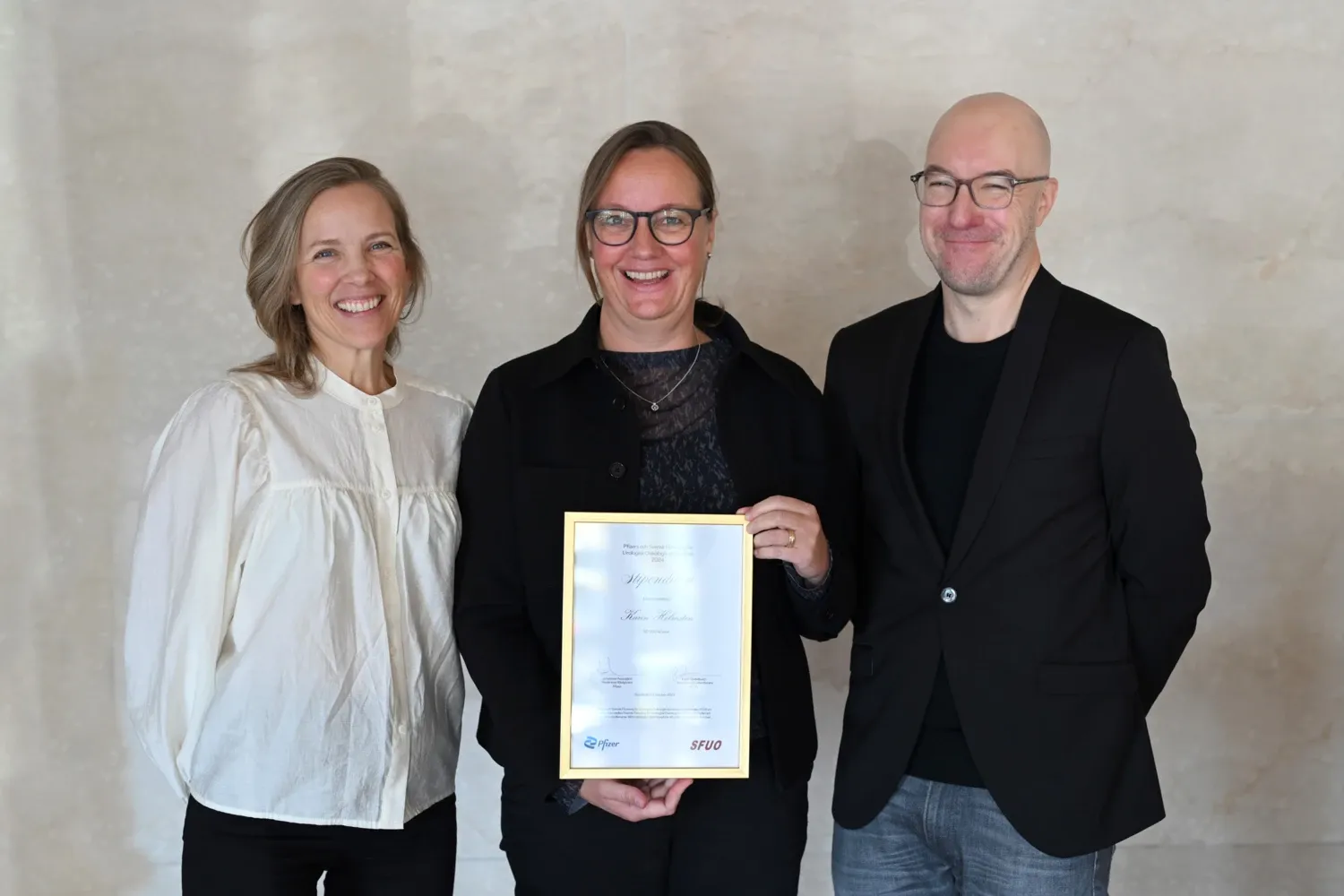 Karin Söderkvist, Karin Holmsten och Johannes Arpegard står bredvid varandra. Karin Holmsten i mitten håller i ett diplom.