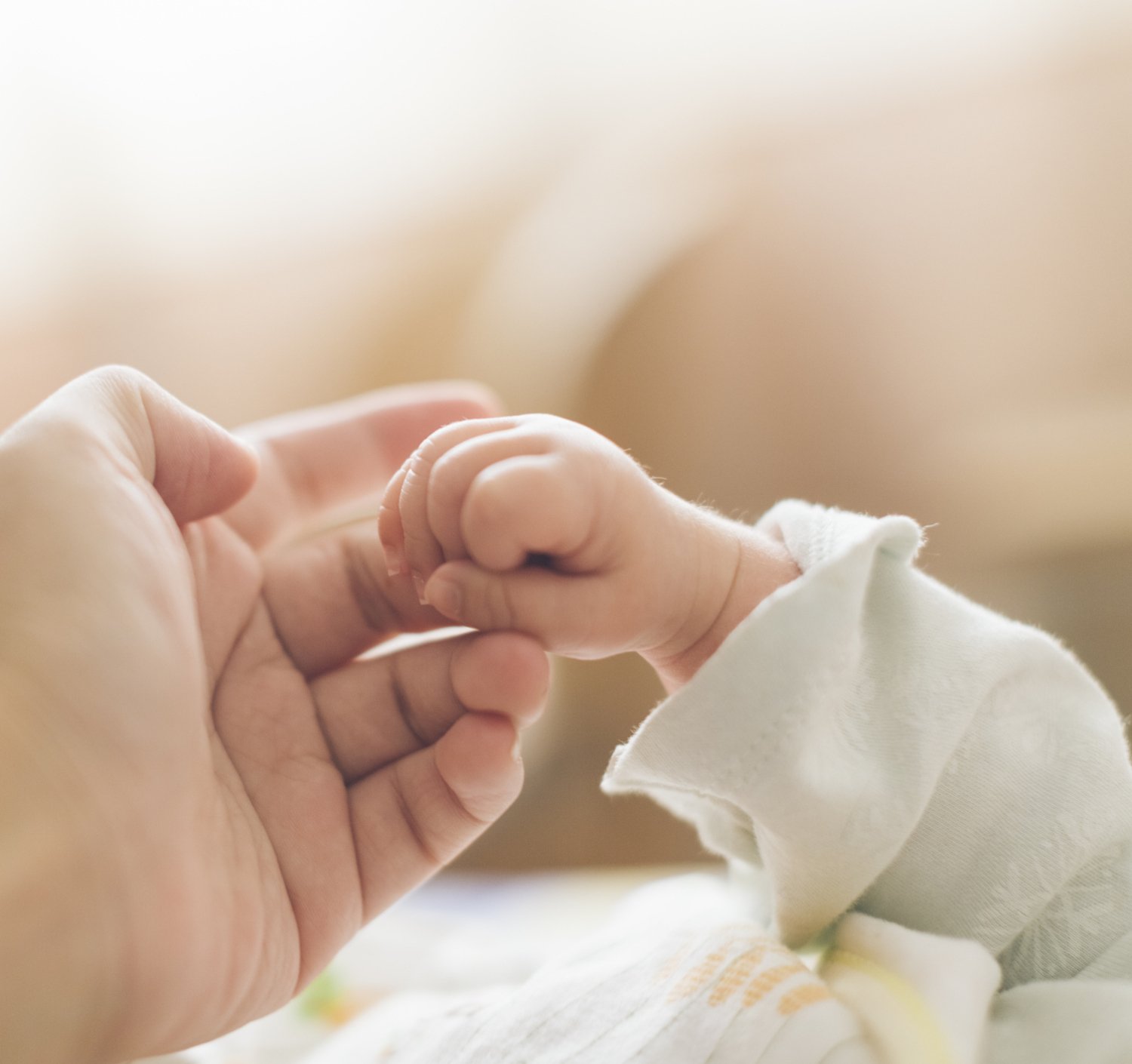 Photo of mother and baby holding hands.