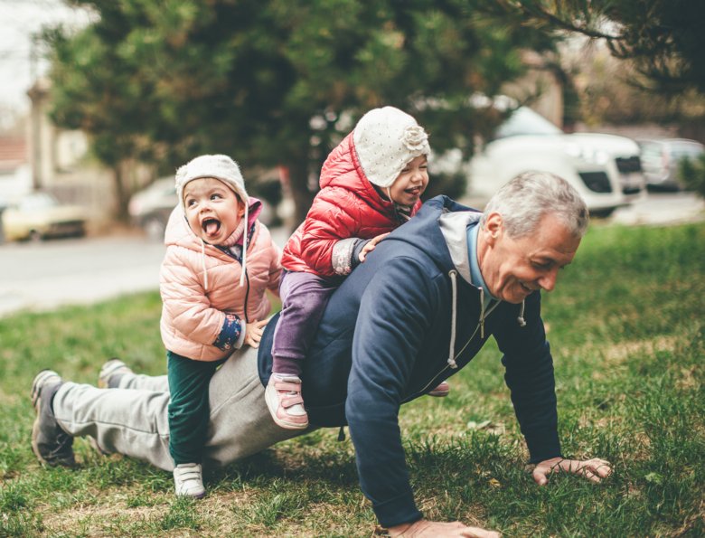 Morfar och barnbarn leker i parken