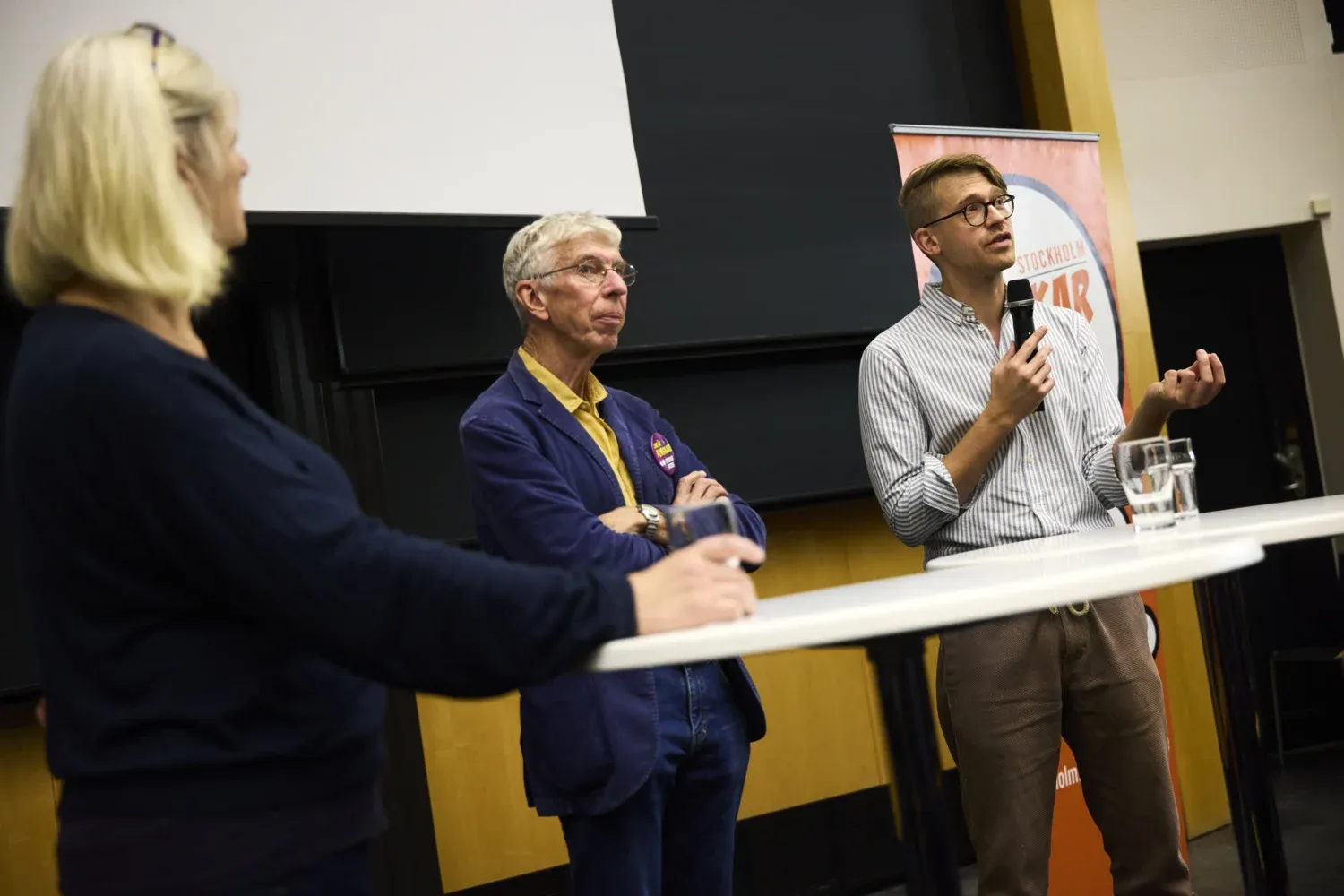 Två män framför ett bord, en av männen håller i en mikrofon.