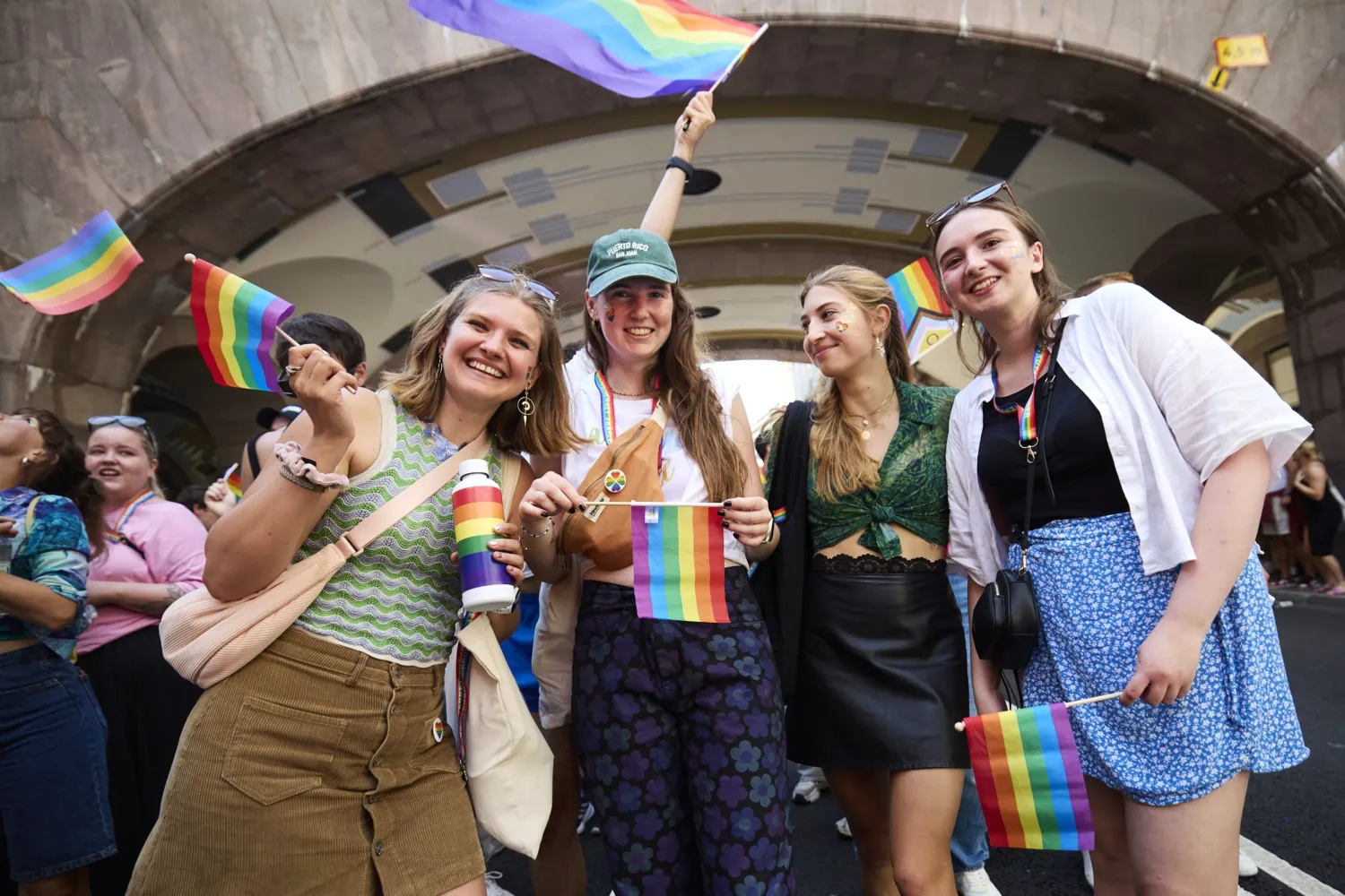 Alina Lapp, Maureen Verdier, Teresa Reindl och Katharina Schormair under paraden på gatan och håller i regnbågsflagor och ler.