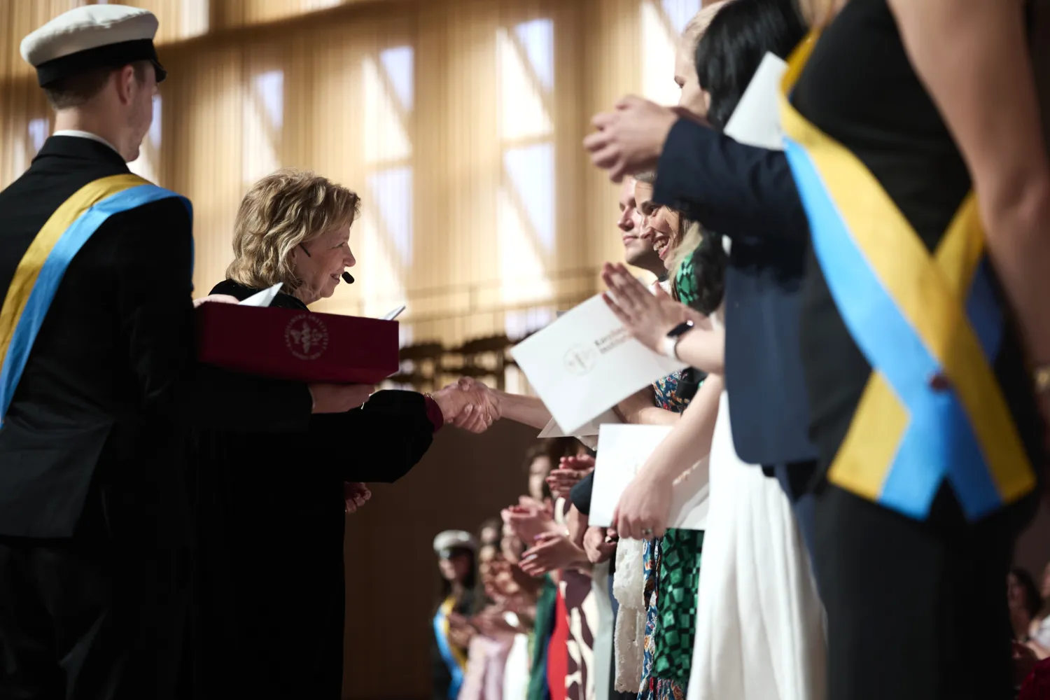 Studenter tar emot sina kuvert från rektor på scen.