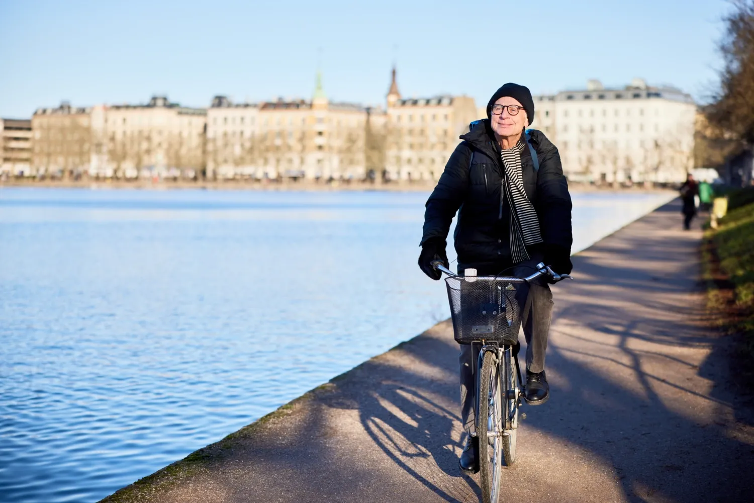 man som cyklar i snön utmed vattnet i stan