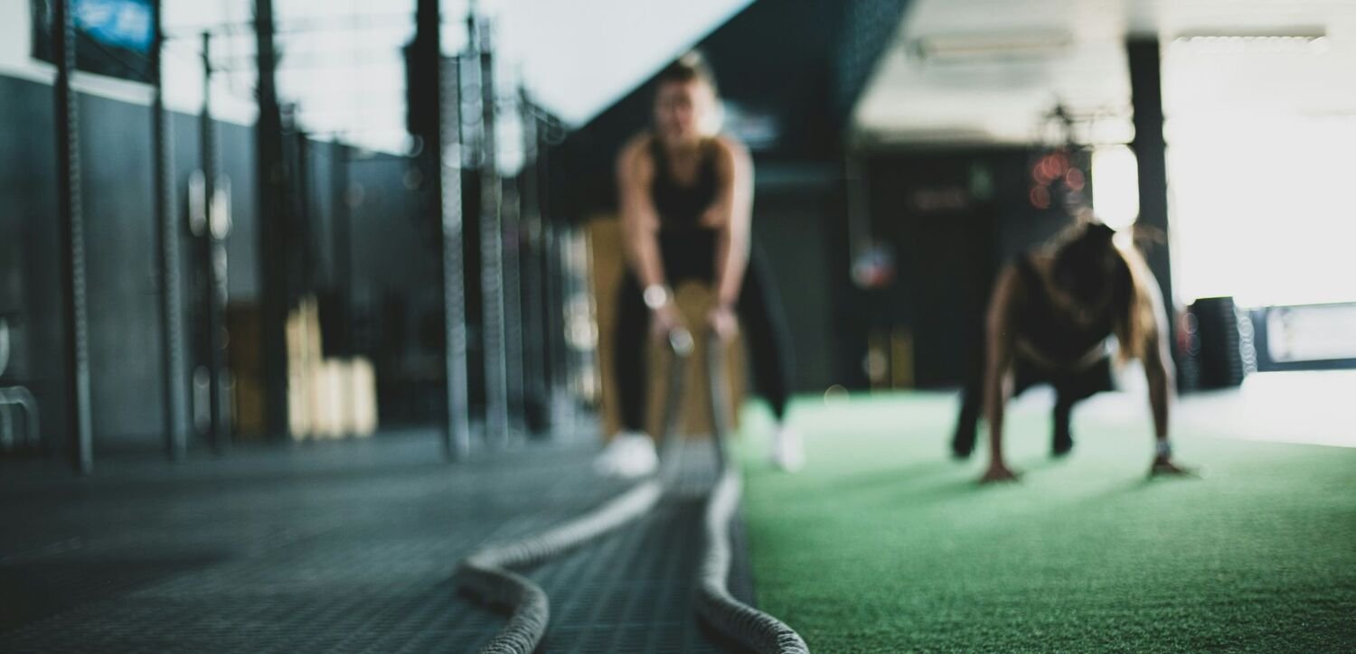 Suddig bild av två personer som tränar med rep i gym.