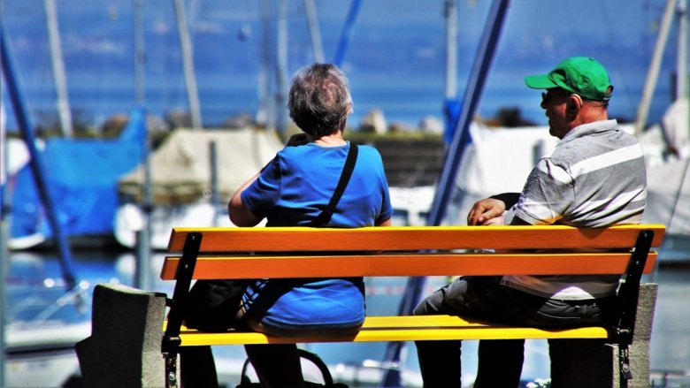 Ett äldre par på en bänk vid småbåtshamnen