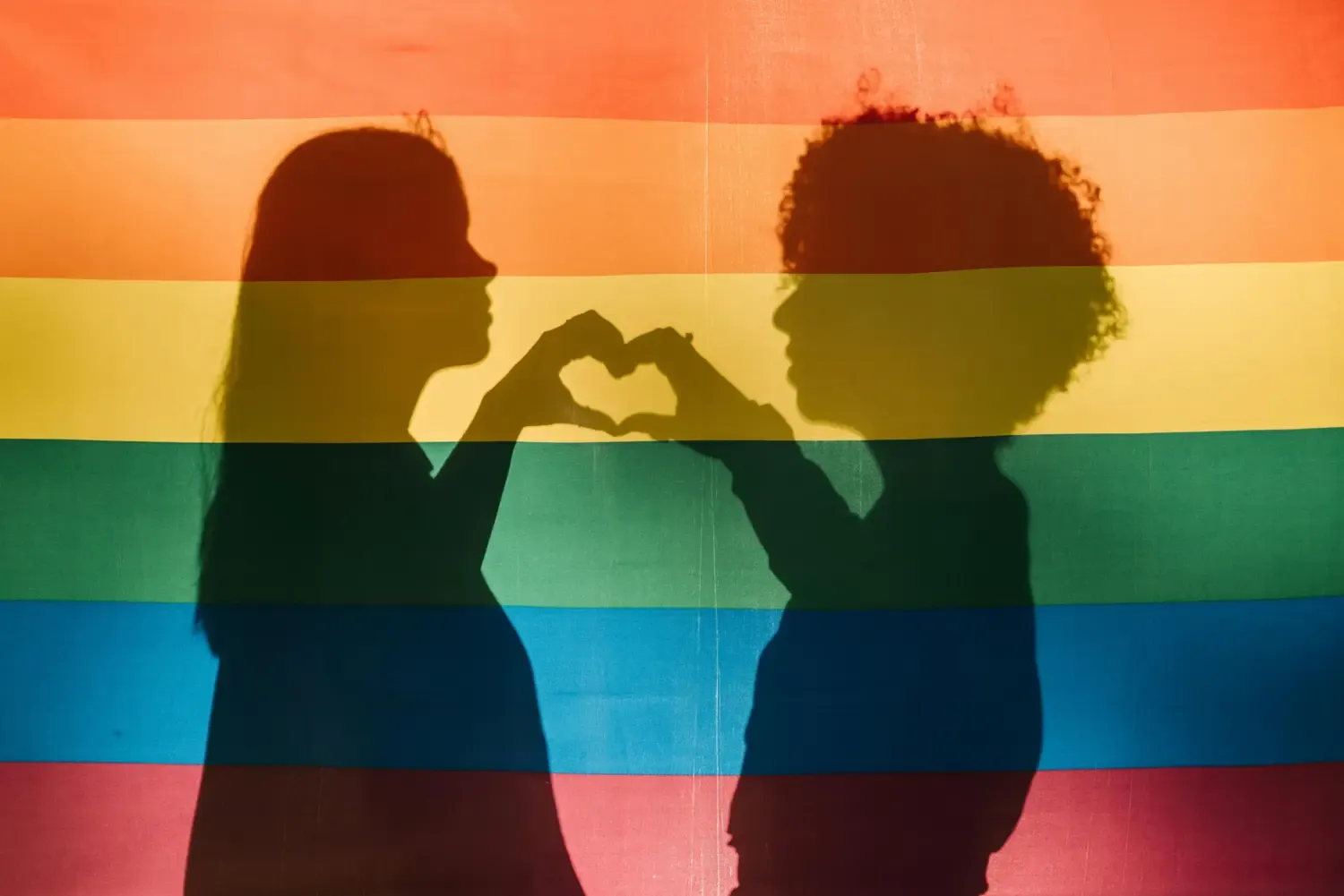 Prideflagga med människor i skugga som håller ett hjärta