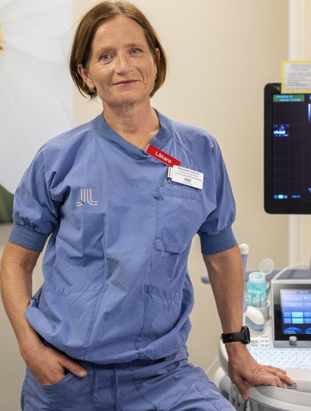 Bilden visar ett porträtt av en kvinna klädd som vårdpersonal.