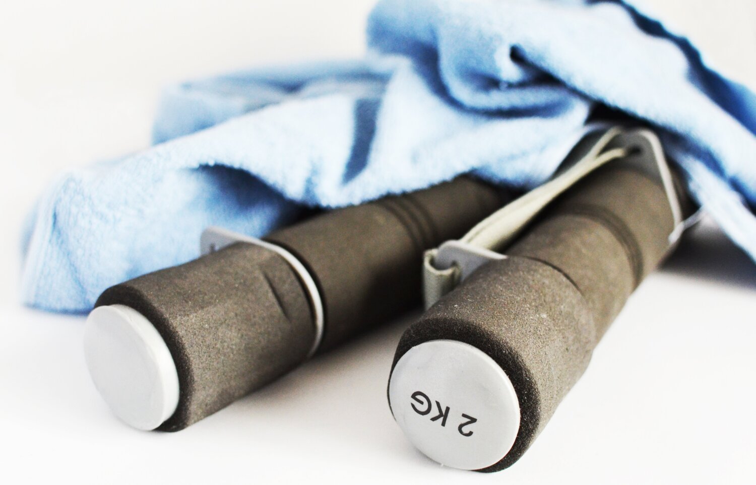 Träningsredskap, handtag 2 kg och en ljusblå handduk.