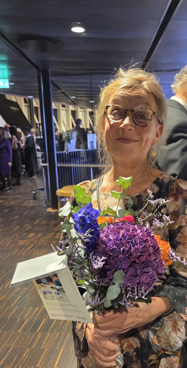 Louise Nygård, professor emerita vid avdelningen för arbetsterapi, mottagare av KI:s stora silvermedalj 2025. Står med en färggrann blombukett i handen.