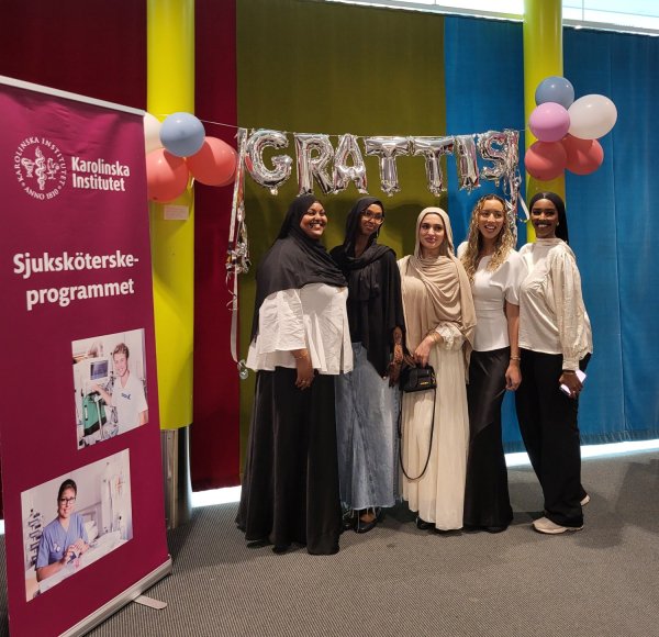 Studenter under en grattis-ballong som firar examen.