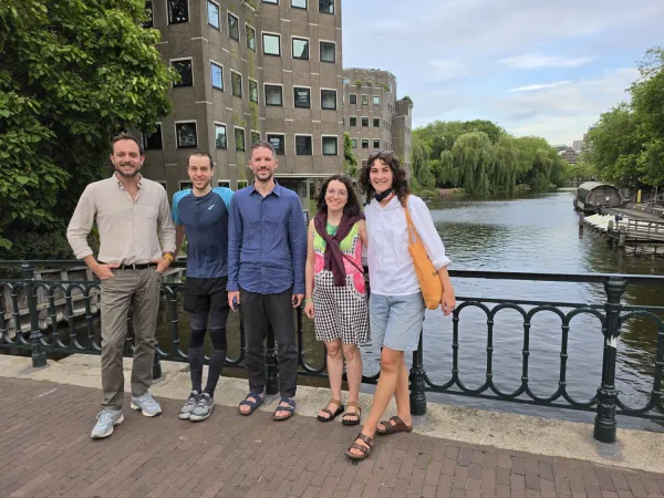Fem personer på en bro över Amsterdams kanaler.