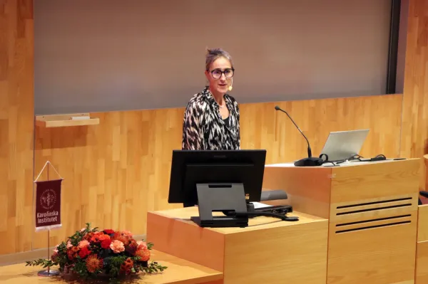 Första huvudtalare, Karin Wadell från Umeå Universitet, står framme vid podiet i H1, ANA 23.