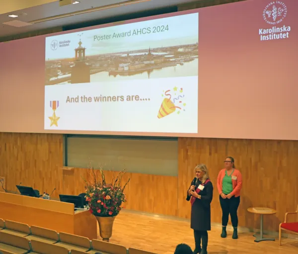 Ing-Mari Dorhn och Nathalie Friesendahl presenterar vinnarna av Poster Award AHCS 2024 på scenen i H1, ANA 23.