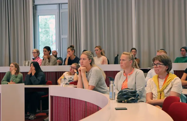 Engagerad publik som sitter i föreläsningssalens bänkar.