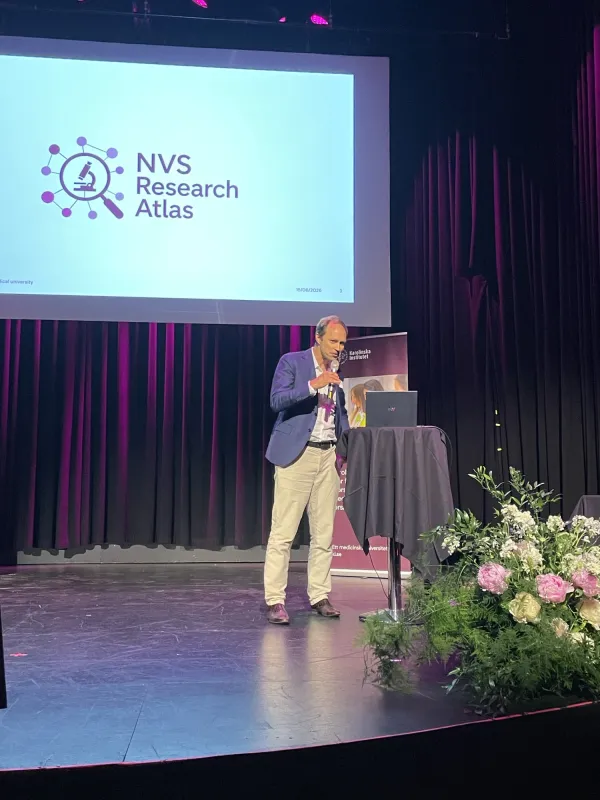 Linus Jönsson på scen med mikrofon i handen berättar om NVS Research Atlas.