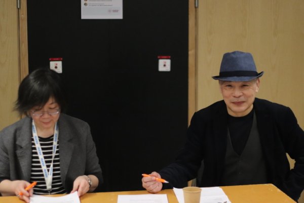 Hong Xu och Yuxi Zhou sitter vid ett bord med penna i hand och papper framför sig.