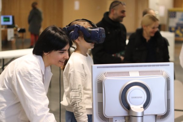 Esra Öncel tillsammans med en ung besökare som har VR-glasögon på sig och få testa sin balans i olika utmaningar.