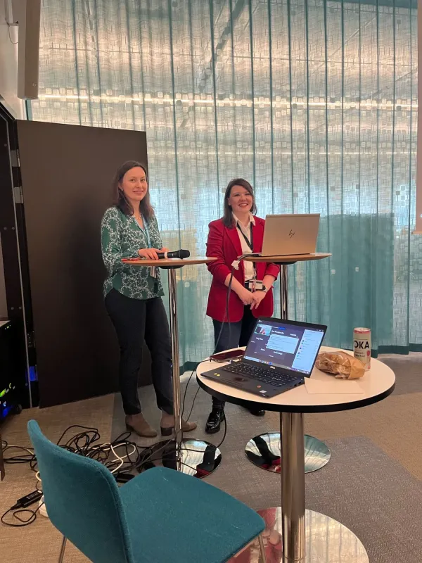 Foto på Tímea Szekerczés and Ewa Kurzejamska som står längst framme i ett större mötesrum med mikrofon i handen.
