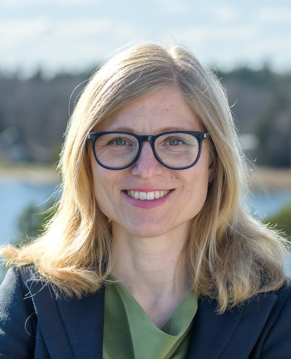 Porträtt av Kajsa Söderhielm, doktorand vid avdelningen för arbetsterapi, NVS, taget ute i naturen med grönska och vatten i bakgrunden..