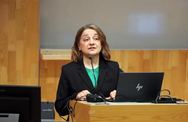 Mandana Fallahpour, nybliven lektor, berättar om sin forskning inom arbetsterapi. En närbild där hon står framme vid podiet i H1 och pratar.