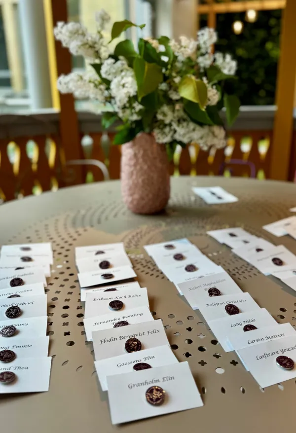 Rader med KI-pins fästa på namnkort, med en blomma i bakgrunden.