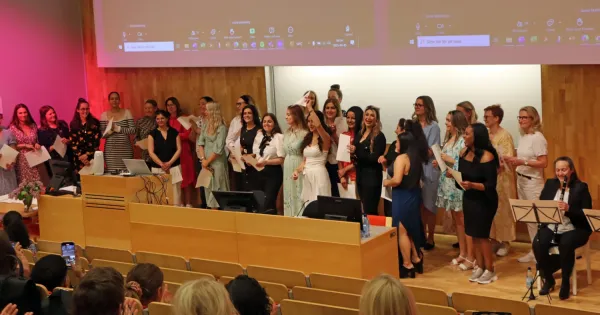 Examen för specialistsjuksköterskor, juni 2025. En grupp står framme vid podiet i H1.