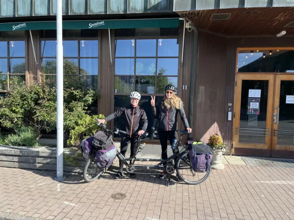 Pernilla och Oskar står framför hotellet med tandemcykeln framför sig.