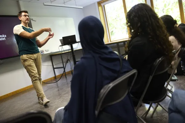 En står framför en skolklass i ett klassrum.