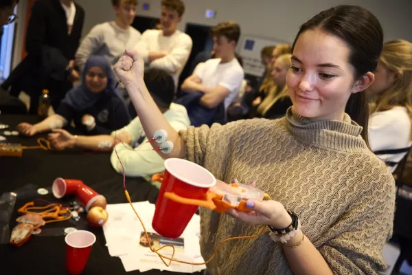 Gymnasietjej håller i en klo och har sladdar på den ena armen.