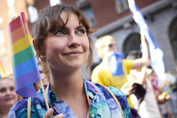 Elinor Lundevall håller i regnbågsflagga och har små glittrande stenar som runt ögonen.