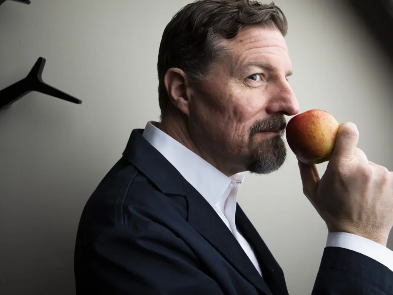 Professorn Johan Lundström håller ett äpple mot näsan.