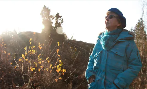 screenshot of the cover with an photo of an older lady standing outside with her face to the sun.