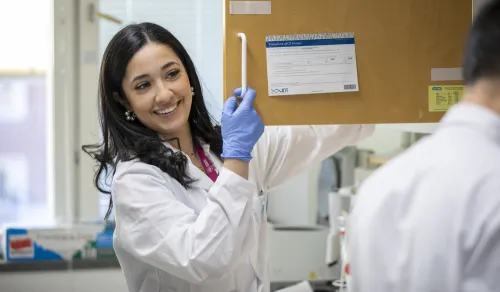 Woman in lab smiling and talking to another researcher.