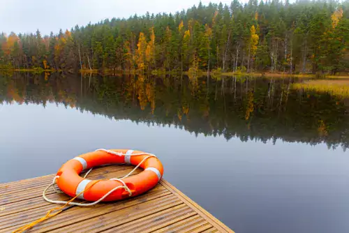 Orange life buoy lying near a lake