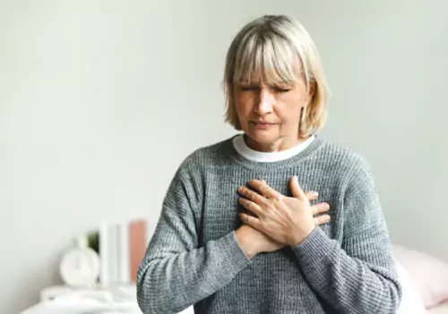 Woman with chest pain sitting on a bed