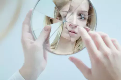 a young woman looking in a bloken mirror