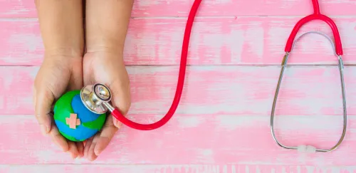 Symbolic illustration: hands holding a globe, which is being examined with a stethoscope.