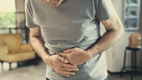 Person bending over in pain covering the stomach.