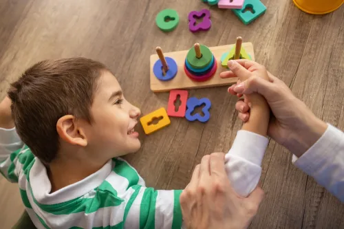 A dedicated female nurse supports a young autistic boy using sensory toys to enhance motor abilities.