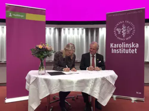 KI&#039;s President and Huddinge municipality’s Director sitting at a table, signing the agreement.