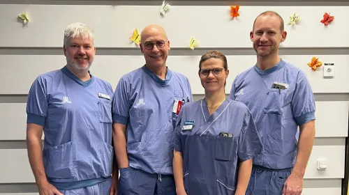 Four people in hospital scrubs. three men one woman