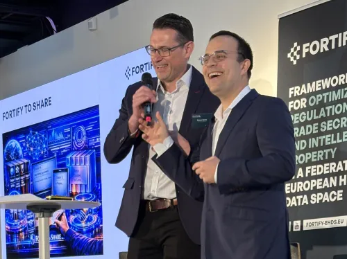 Two men standing on a podium during a conference. They are happy.